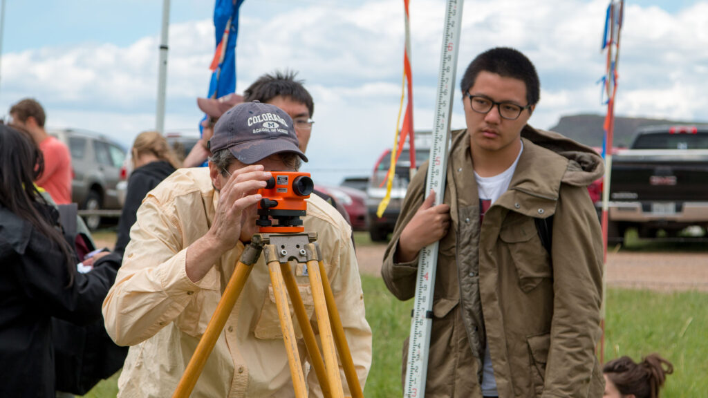 Civil engineering students working with a camera-type device during their field session